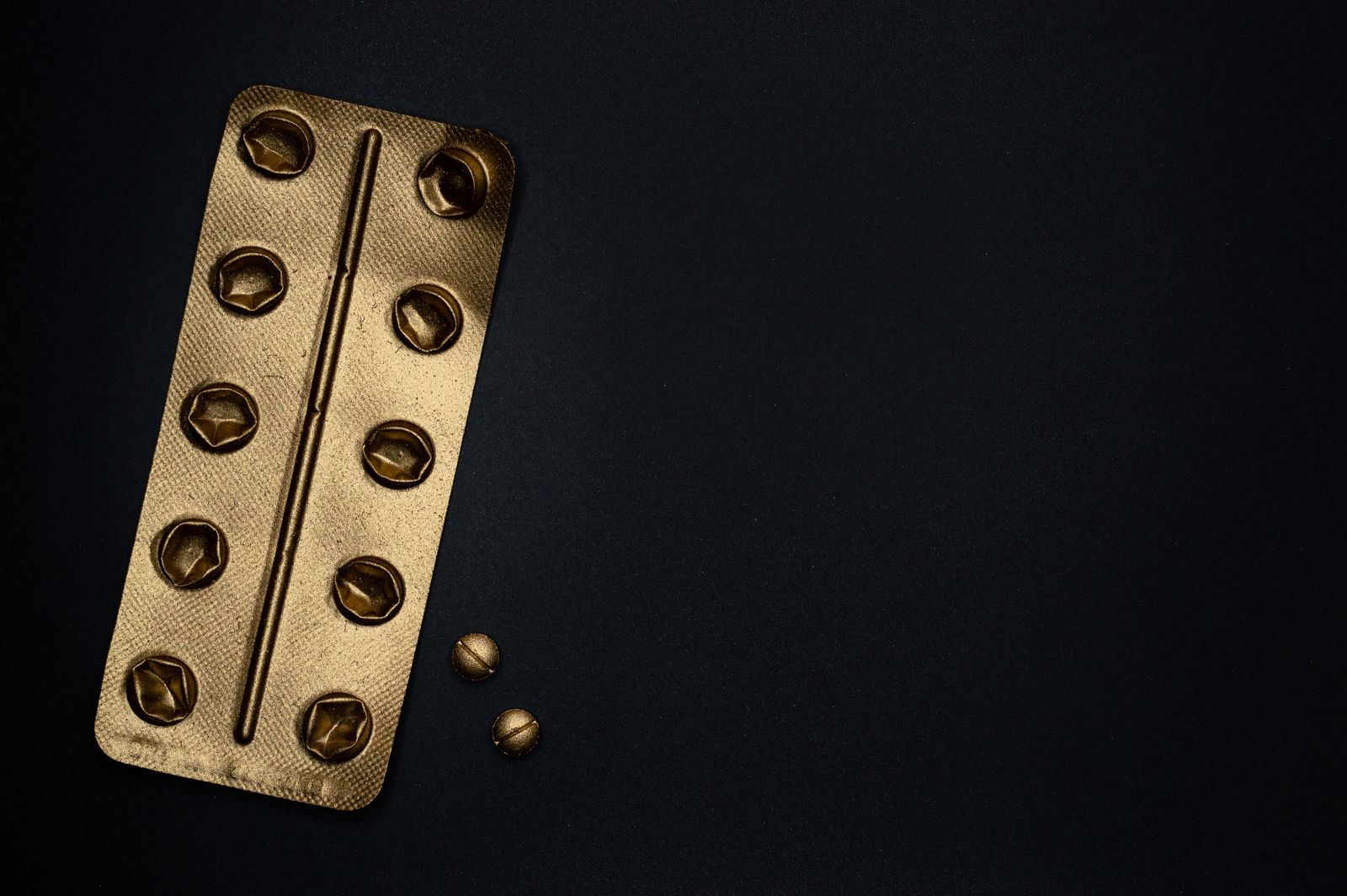 Golden blister pack of tablets on a black surface